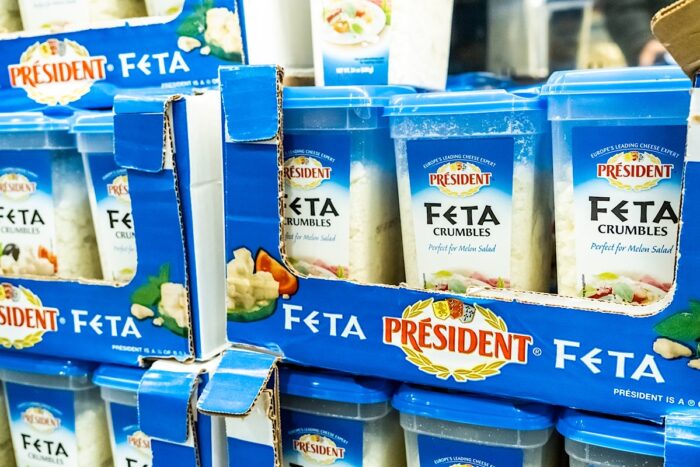 Plastic containers of President brand imported feta cheese crumbles on display for sale at a local mega store.