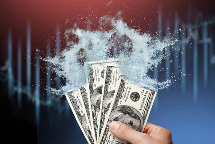 Close up of a person holding American cash that is disintegrating into dust. Inflation concept - American-made products