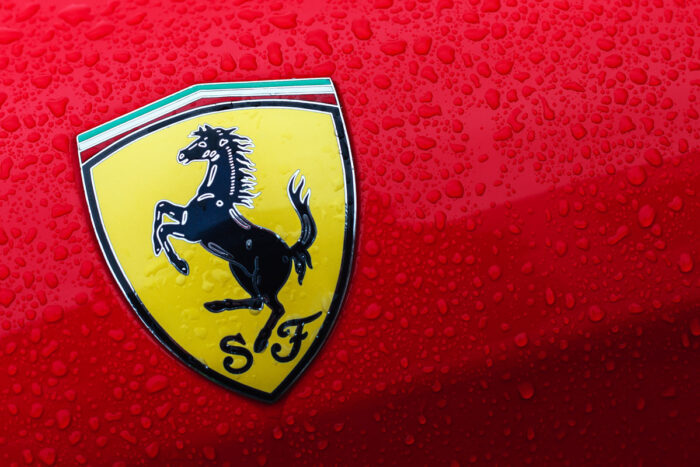 A close-up of the Ferrari logo on a red car with drops of water.
