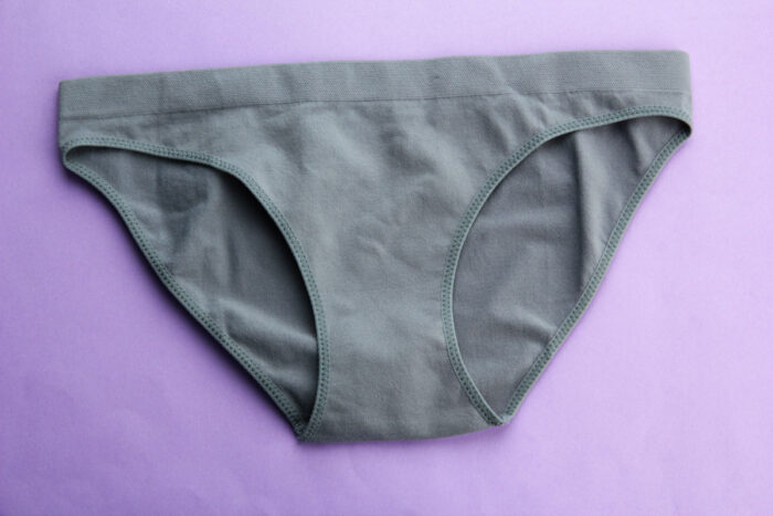 Close up of womens gray underwear on a purple background.