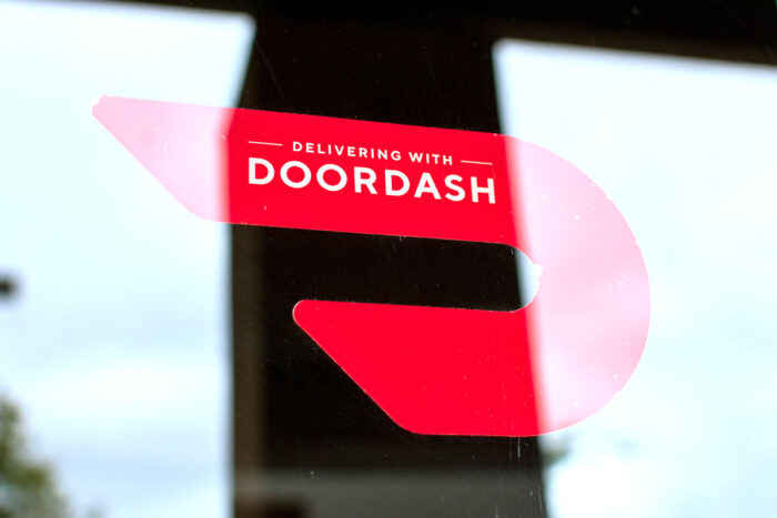 A red sticker decal on a restaurant door advertising delivery service available through DoorDash.
