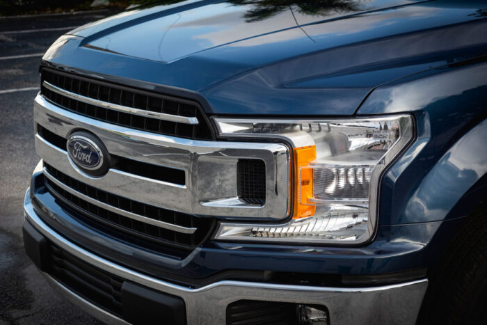 front view of a blue Ford F-150 XLT. Headlights, Chrome grill and bumper.