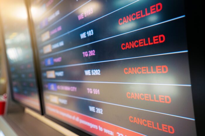 flights cancellation status on flights information board in airport; airline refunds concept