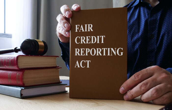 Close up of person holding a brown book that reads 'Fair Credit Reporting Act' - pre-adverse action notice, managed labor solutions employment lawsuit, fcra lawsuit