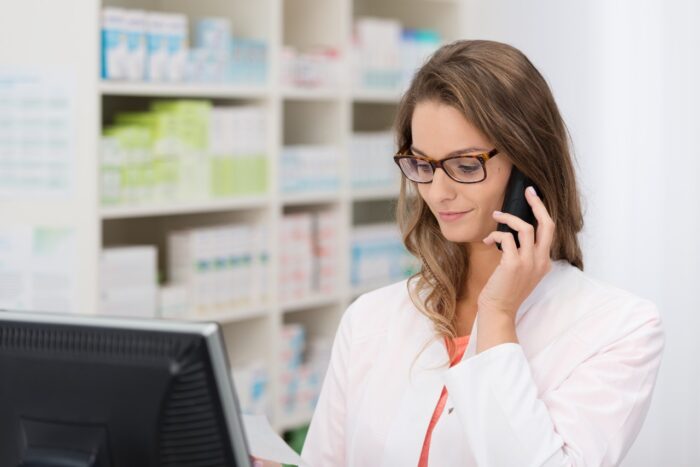 female pharmacist taking call on pharmacy phone as she discusses a prescription with a patient, delta drugs pharmacy has settled over recored calls.