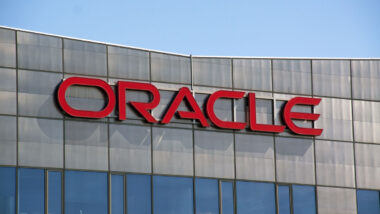 Close up of Oracle signage on exterior of a building against a blue sky.
