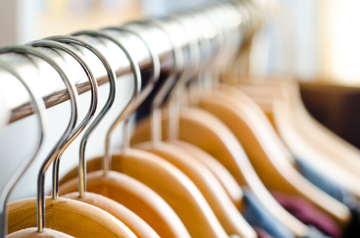 Close up of wooden hangers on a clothing rack.