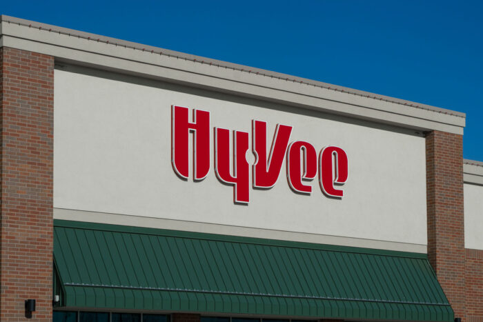 Close up of Hy-Vee logo on an exterior building against a blue sky.