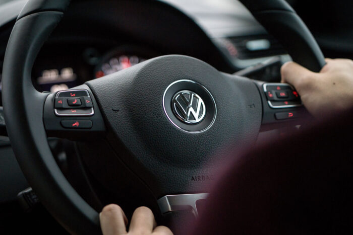 Close up of a Volkswagen emblem on a steering wheel.