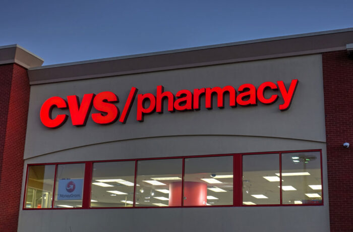 Close up of CVS pharmacy signage on exterior of building against a dark blue sky.