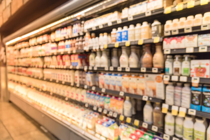 Defocused blurred selection of dairy products in open front cold fridge at retail store in USA - premier protein, lyons magnus, national beverage recall