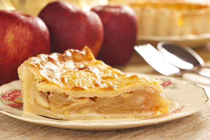 Close up of a slice of apple pie with apples in the foreground - Mrs. Smith’s brand frozen apple pies