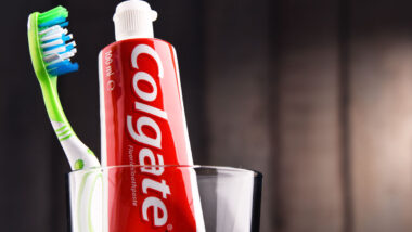 Close up of Colgate toothpaste with a toothbrush in a glass jar.