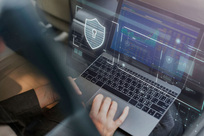 Close up of a woman's hands using a laptop computer with a security overlay. Data breach concept.