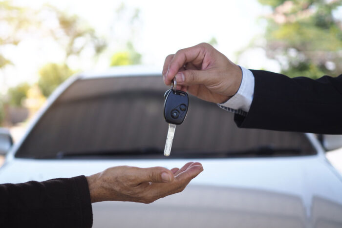 Close up of a car salesman's hands giving keys to another.