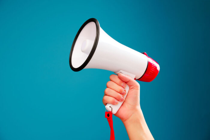 A person holding a megaphone against a blue background.