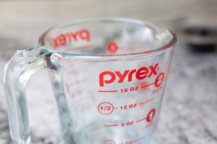 A closeup view of a Pyrex measurement cup glass on the kitchen counter.