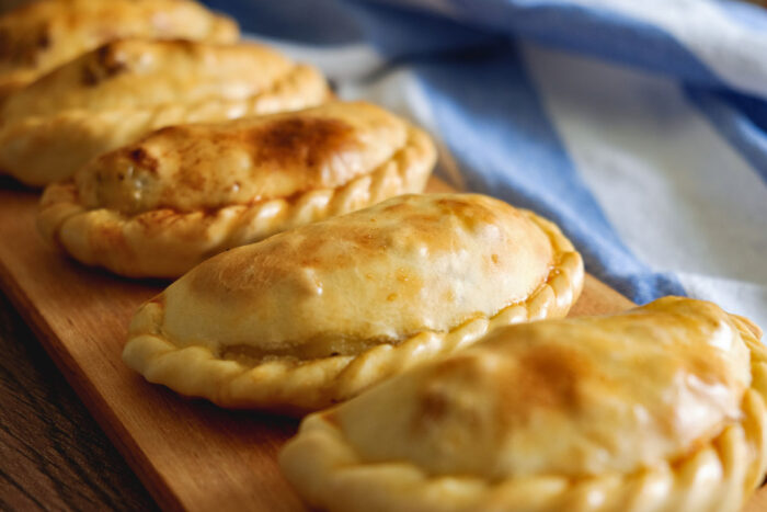 Traditional Argentinian baked empanadas on a wooden plate.