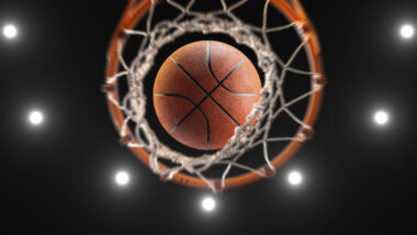 Bottom view of a basketball going through a basketball hoop.