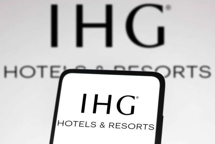 IHG Hotels and Resorts (IHG) logo seen displayed on a smartphone and on the background.
