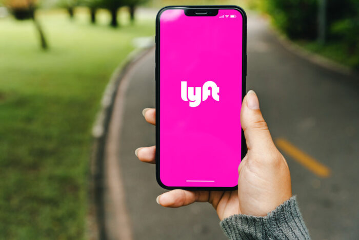 Girl in the park holding a smartphone with Lyft app on the screen.