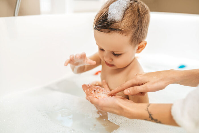 Baby playing with bubbles in a bathrub.