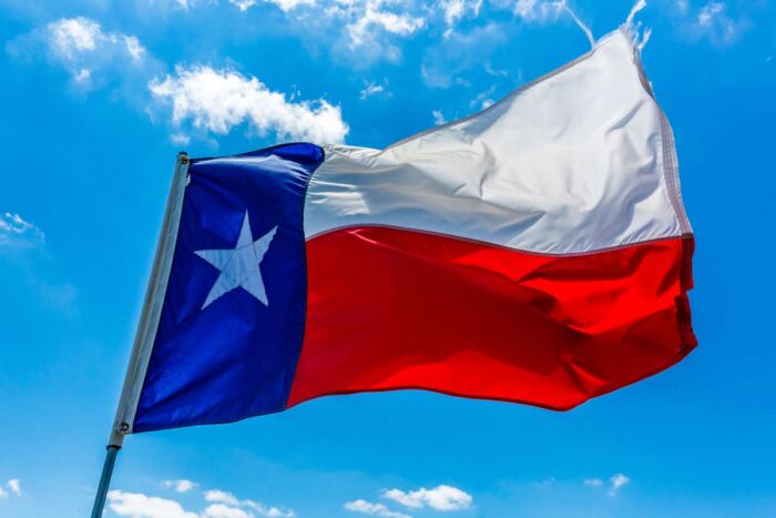 Close up of a Texas flag against a bright blue sky.