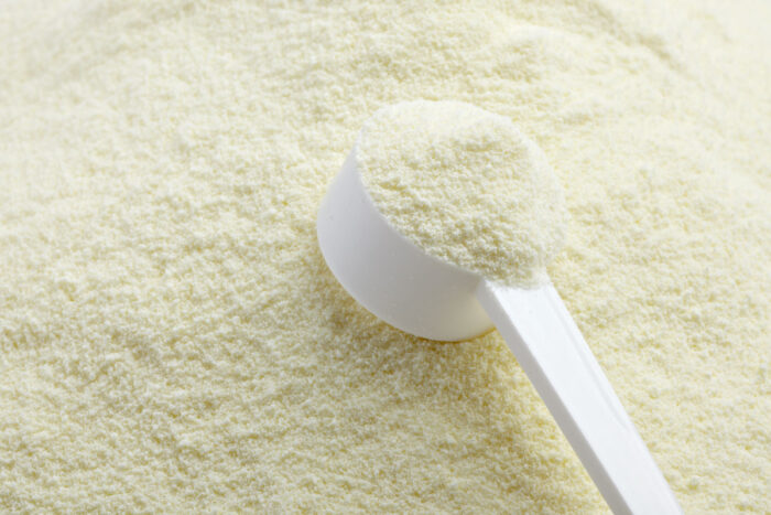 Close up of a white scooper on top of powdered milk.