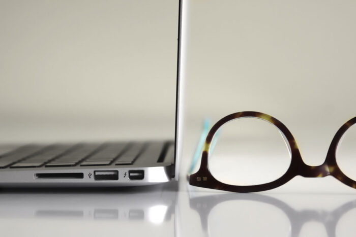 Close up of brown framed glasses next to a laptop on a table - LensCrafters class action