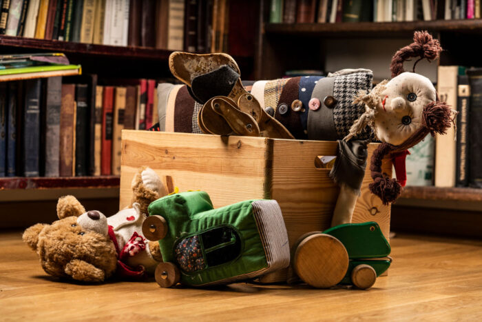 Children toys in a wooden box, books in the background on wooden floor - children's recalls