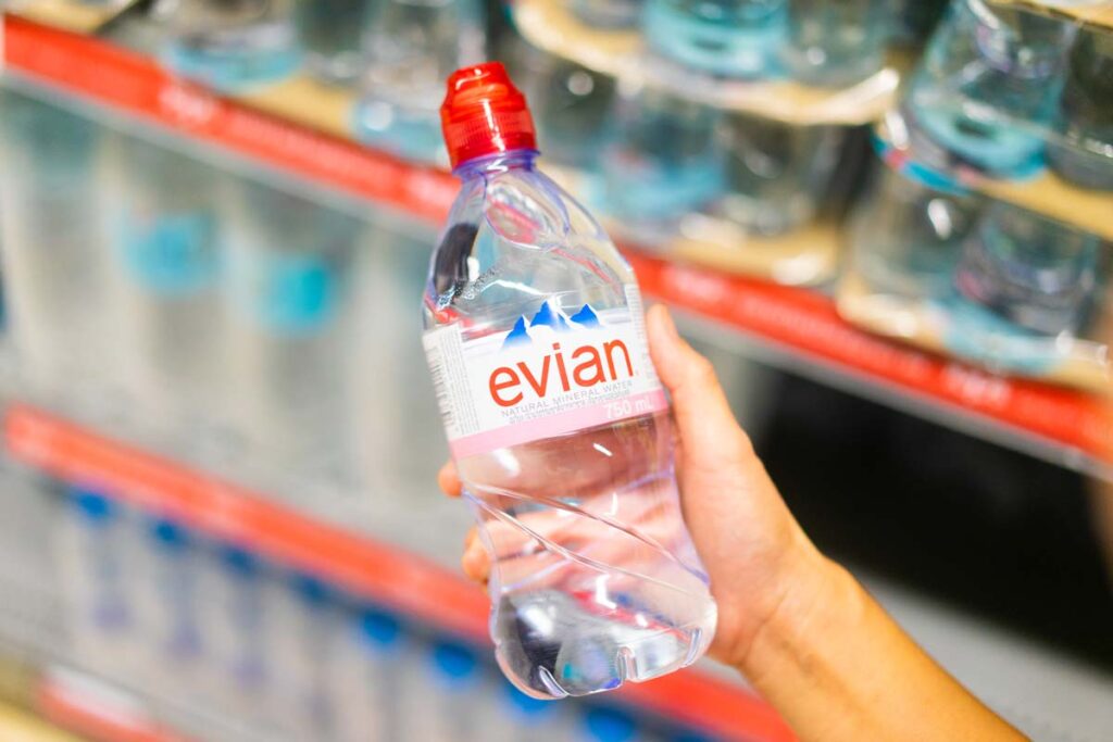Close up of a hand holding an Evian water, representing the Evian class action.