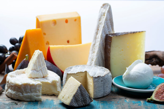 An assortment of cheese on top of a table against a white background.