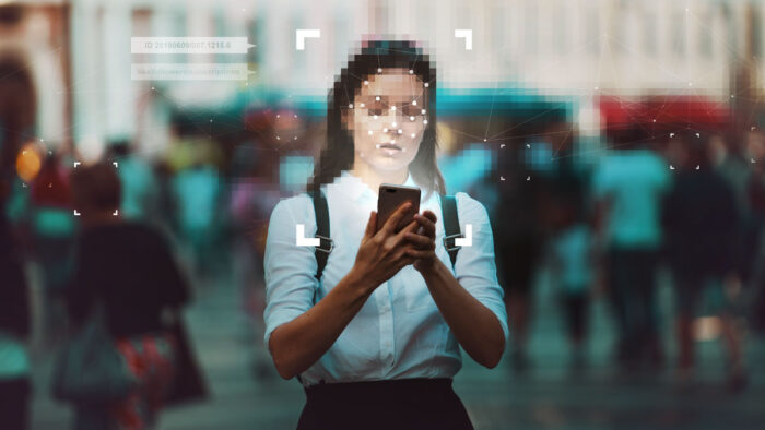 Young woman using a smartphone with a facial recognition overlay.