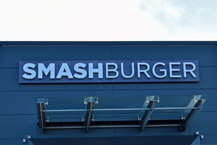 Close up of Smashburger signage on exterior of building against a blue sky - class action settlement