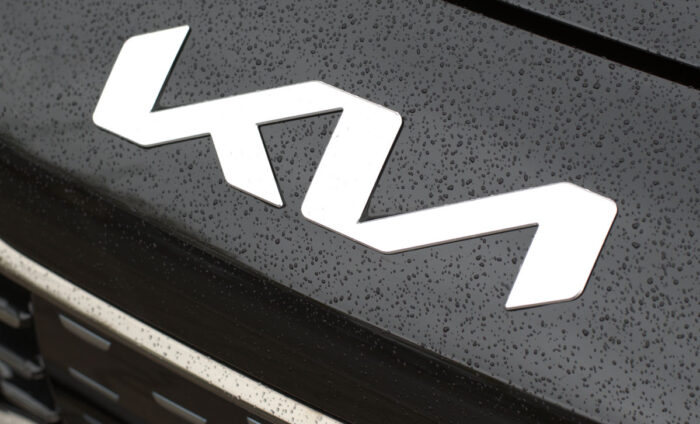 KIA Motors new angular logo on black hood of red Kia Rio with water drops.