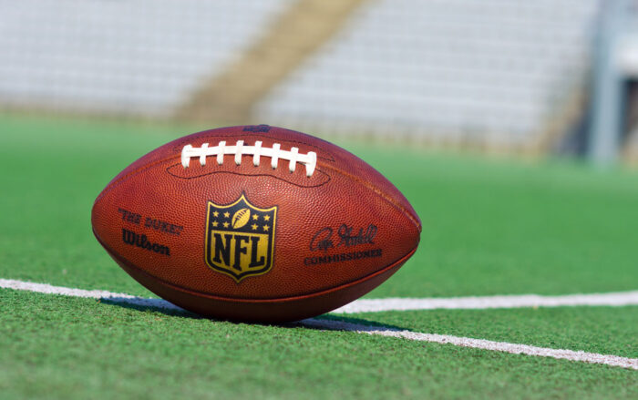 Close up of a football with the NFL logo on a football field - class action