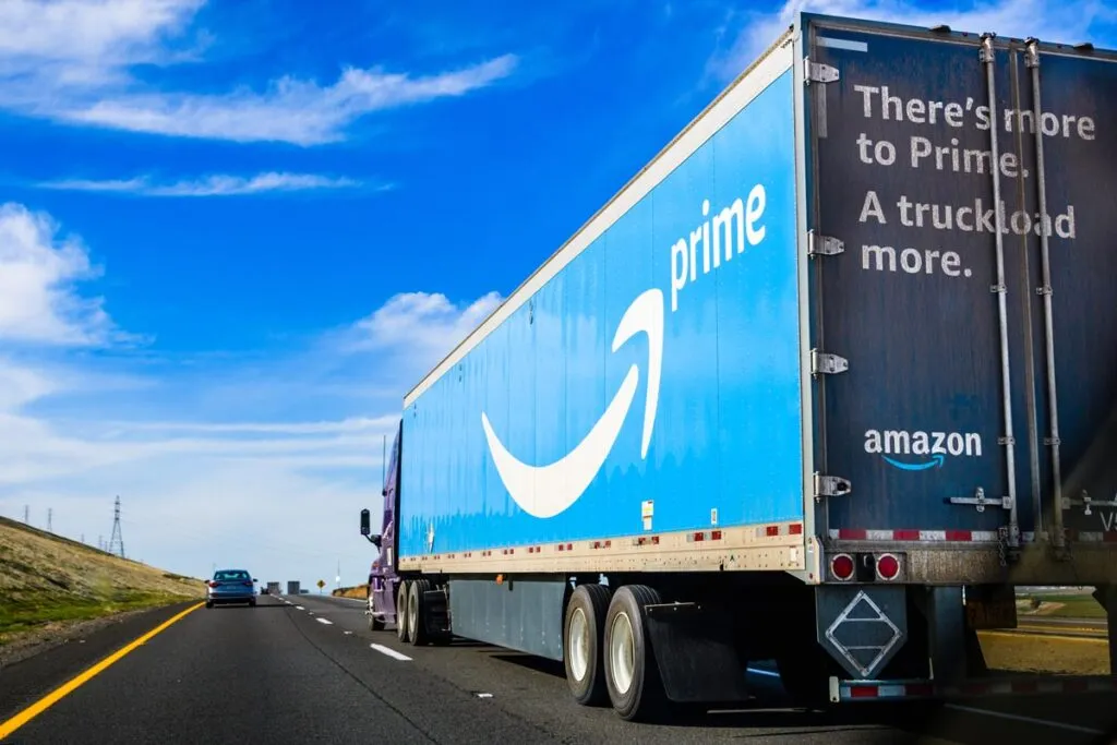 Amazon truck driving on the interstate, the large Prime logo printed on the side.