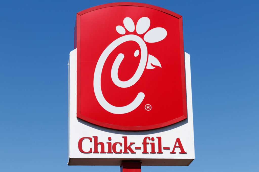 Close up of Chick-fil-A signage against a blue sky.
