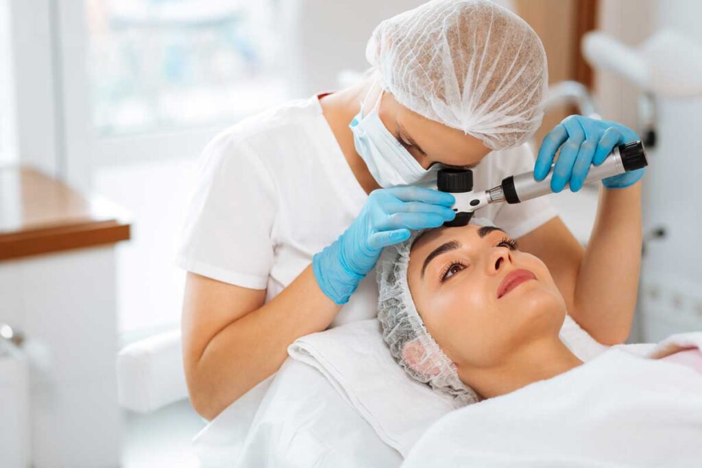 Skilled female dermatologist using a professional dermatoscope while doing a skin examination, representing the Forefront Dermatology data breach settlement.