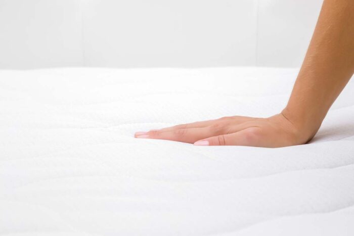 Close up of a woman's hand pressing on white mattress - Nectar mattress class action