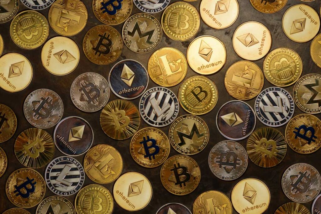 Close up of a variety of different cryptocurrency coins against a wood background.