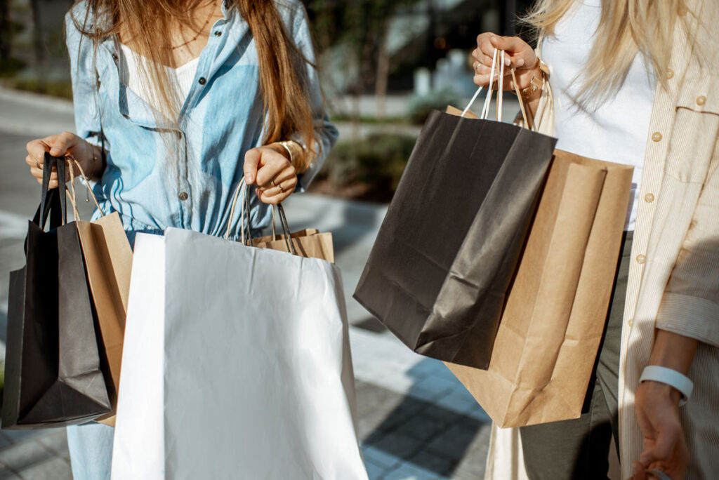 Women holding shopping bags outdoors while shopping, close-up view on the empty paper bags.