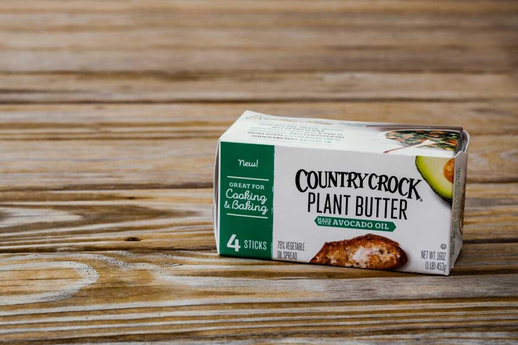 Close up of Country Crock butter made with plant based Avocado oil against a wood background.
