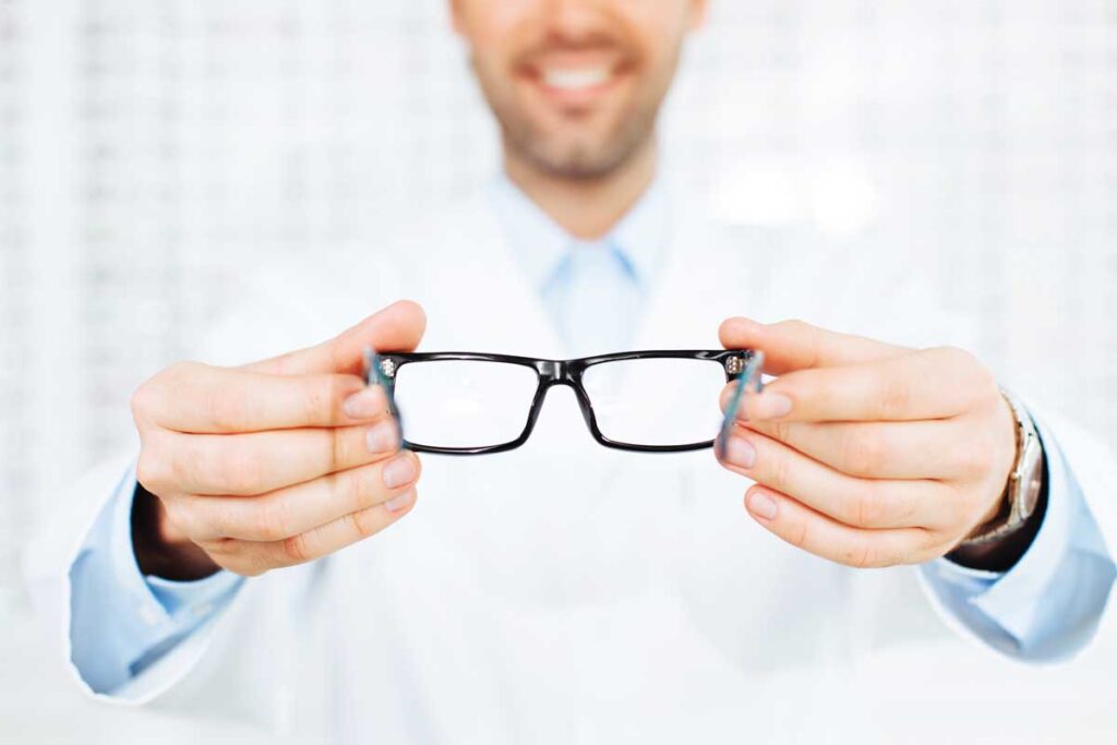 Closeup of optician, optometrist giving eyeglasses to try.