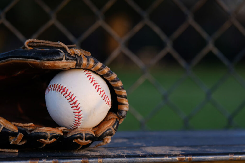 Close up of baseball in glove close up sitting on dugout bench - MLB class action, minor league wage
