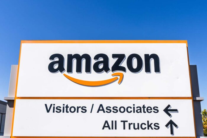 Amazon logo and Smile symbol displayed at one of their fulfillment centers; information regarding entrance for visitors, associates and trucks provided below.