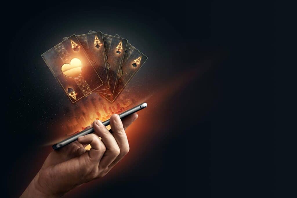 Black playing cards coming out of a smartphone. Online gambling concept, representing the Chumba Casino, Luckyland Slots and VGW games class action lawsuit settlement.