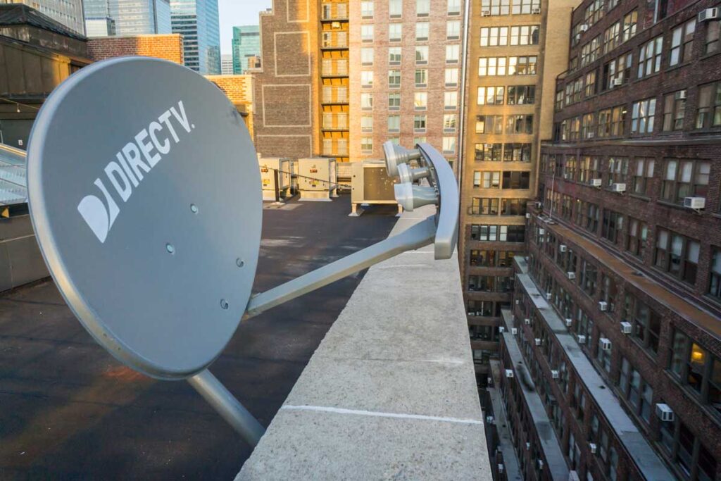 A DirecTV satellite dish on the rooftop of a building in New York, representing the DirecTV class action lawsuit settlement.
