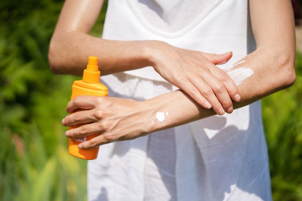 A young girl in a white summer dress applies sunscreen gel to her arms and shoulders, representing the Banana Boat sunscreen class action.