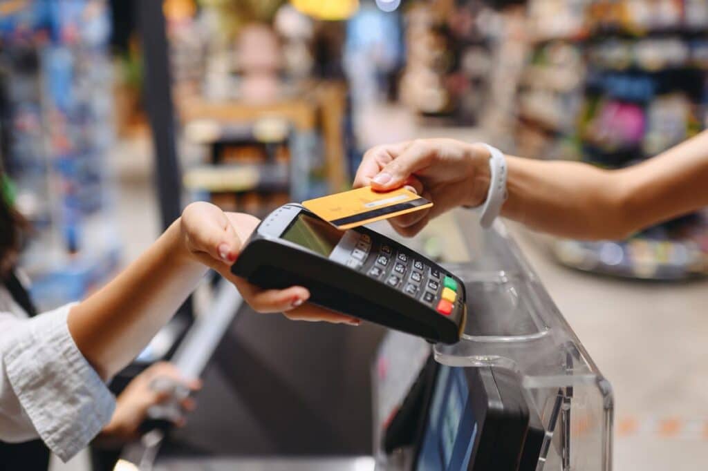 Close up of a womans hand placing her credit card atop a bank terminal machine, representing the Bangor Savings Bank overdraft fees settlement.